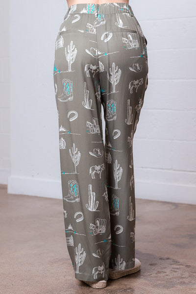 Pants with a desert-themed pattern on a wooden floor.