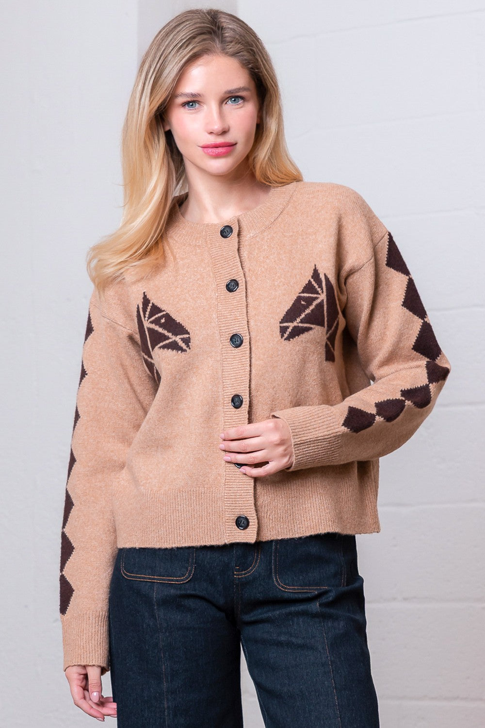 Woman wearing a beige cardigan with brown geometric patterns against a white background
