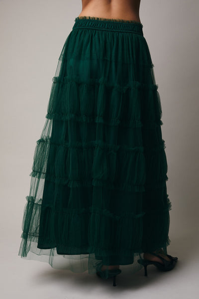 Green tiered skirt worn by a person on a plain background