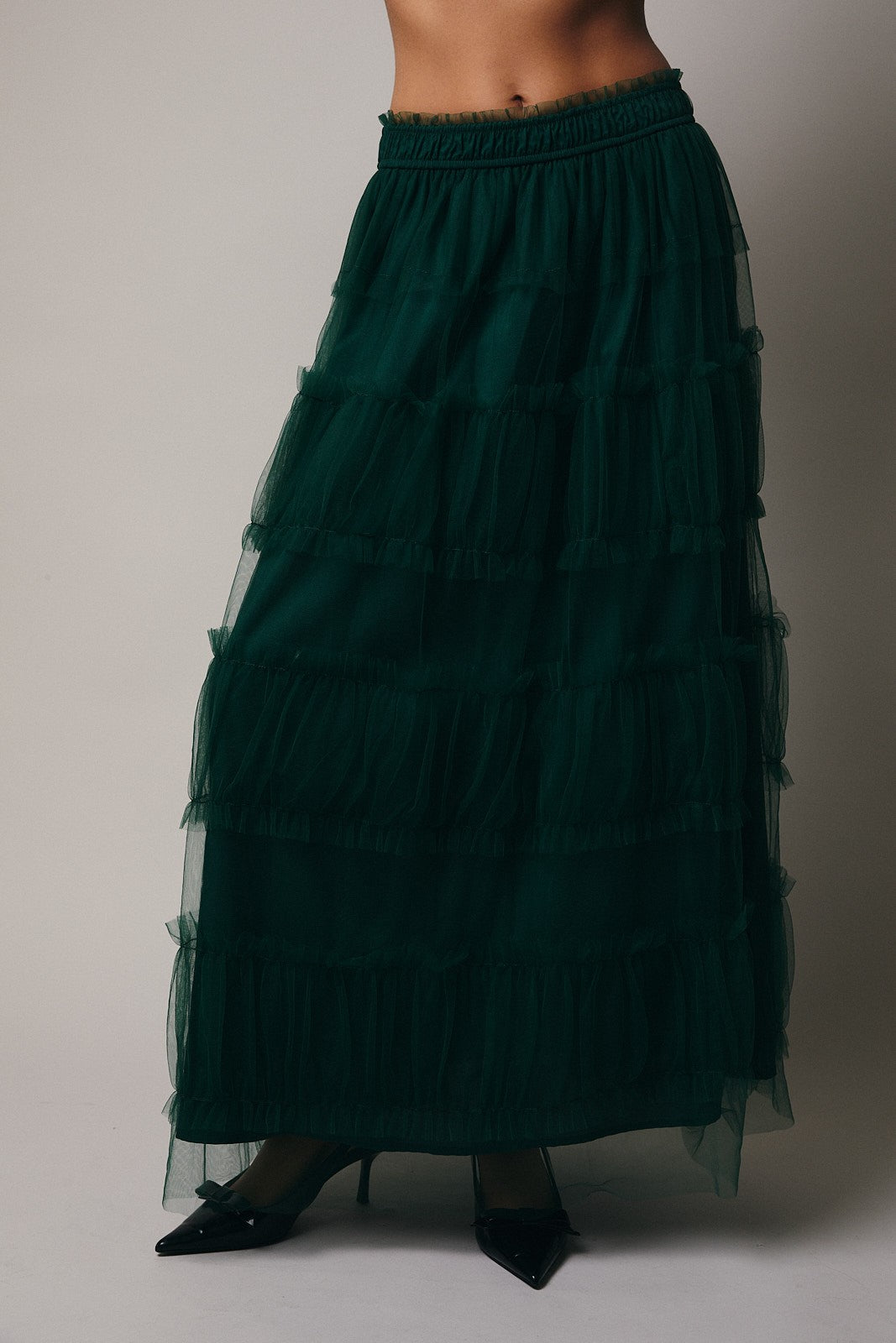 Green tiered skirt worn by a person on a plain background