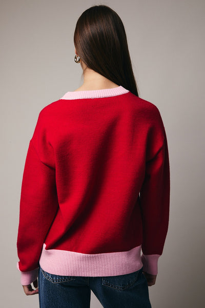 Person wearing a red sweater with a pink collar against a gray background