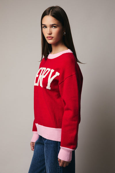 Person wearing a red sweater with pink accents and 'HAPPY' text on a neutral background