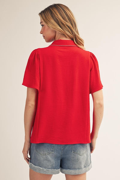 back of model wearing a red v neck blouse with cuffed jean shorts