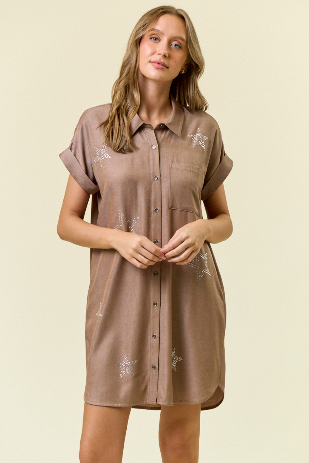 Woman wearing a brown dress with star patterns on a beige background
