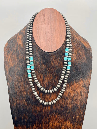 Necklace with silver and turquoise beads on a wooden mannequin