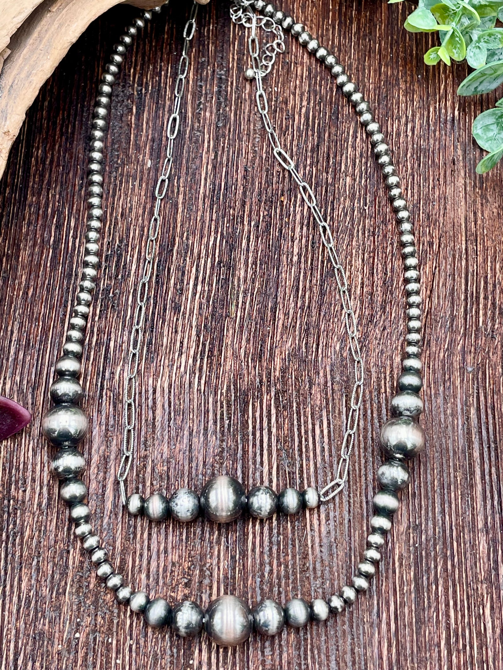 Necklace with silver beads and chain on a wooden surface