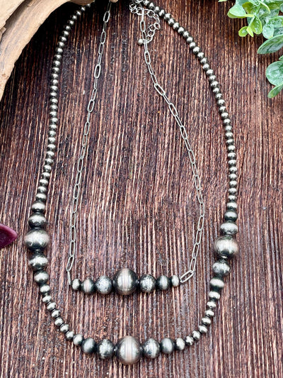 Necklace with silver beads and chain on a wooden surface