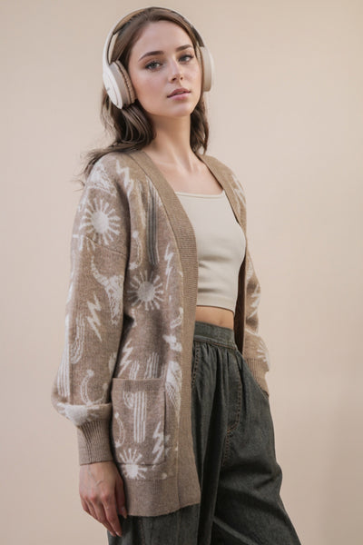 Woman wearing a patterned cardigan over a tank top with headphones on a beige background