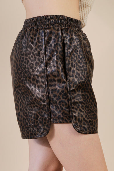 Leopard print shorts worn by a person on a beige background
