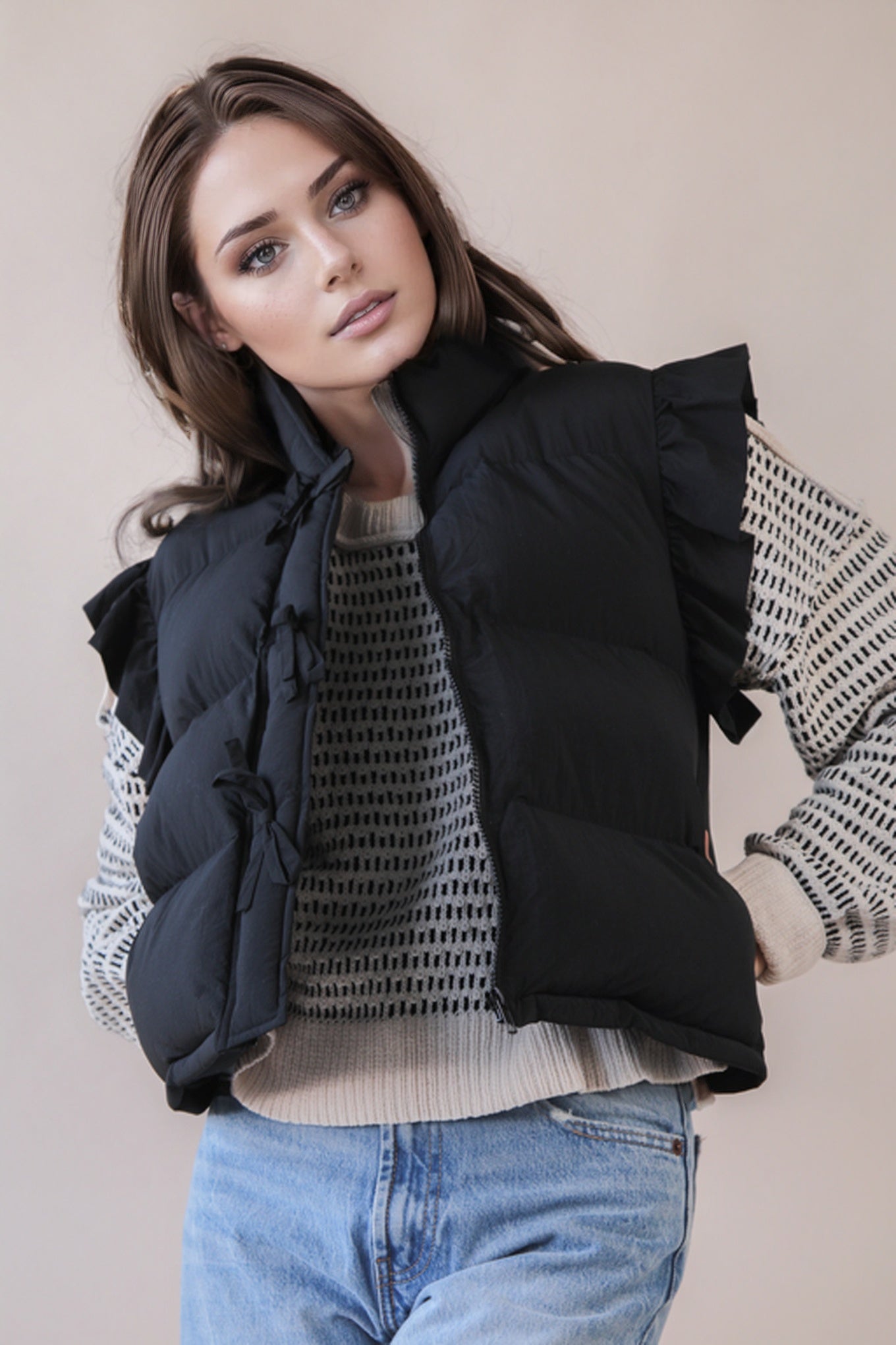 Woman wearing a black puffer vest over a patterned sweater with a plain background