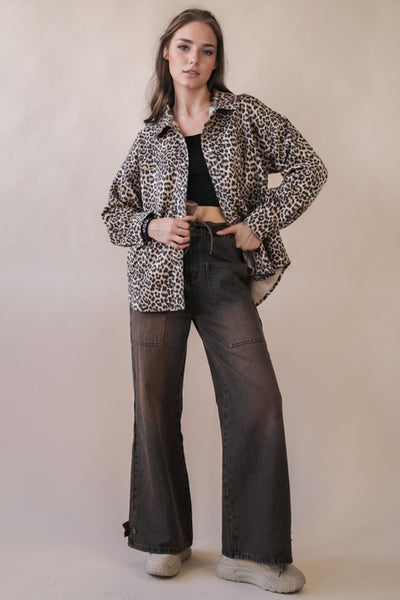 Woman wearing a leopard print jacket and black pants on a beige background