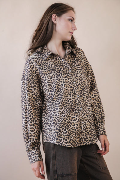 Woman wearing a leopard print shirt against a plain background