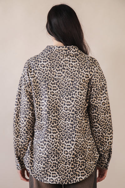 Person wearing a leopard print shirt against a beige background