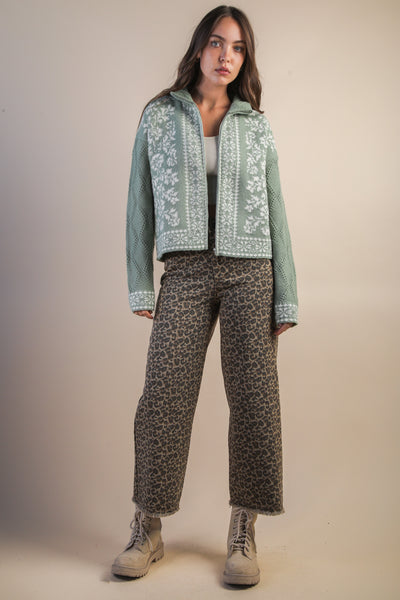 Woman wearing a green patterned jacket and pants on a beige background