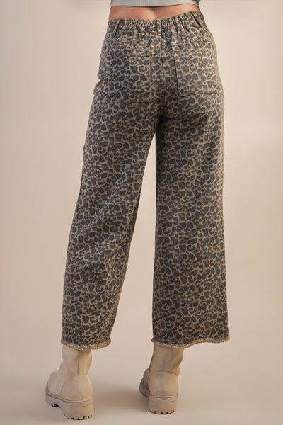 Leopard print pants worn by a person on a beige background
