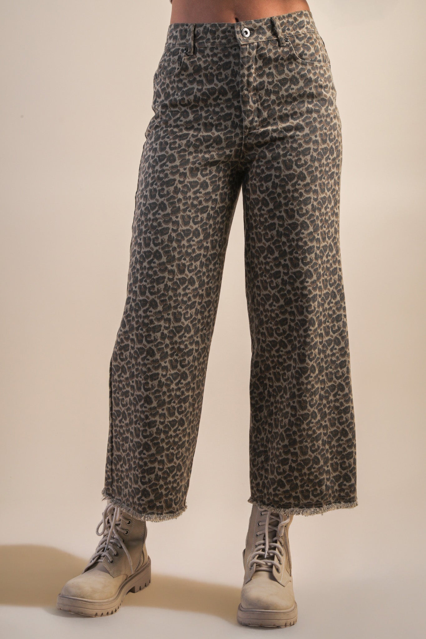 Leopard print pants worn by a person on a beige background
