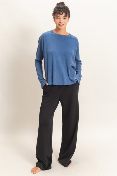 model wearing a blue shirt & black pants with a light background