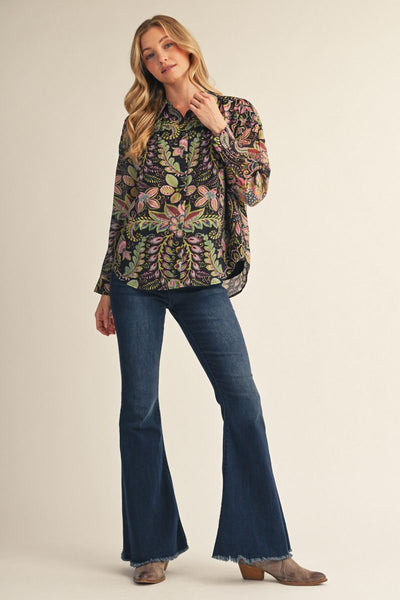 model wearing multicolored floral top with jeans and boots on a beige background