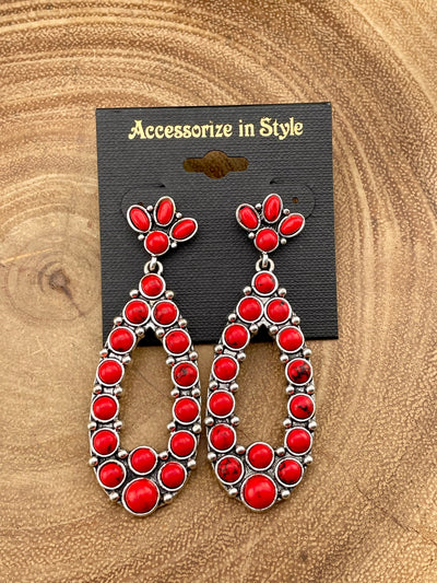 Red and silver earrings on a 'Accessorize in Style' card against a wooden background