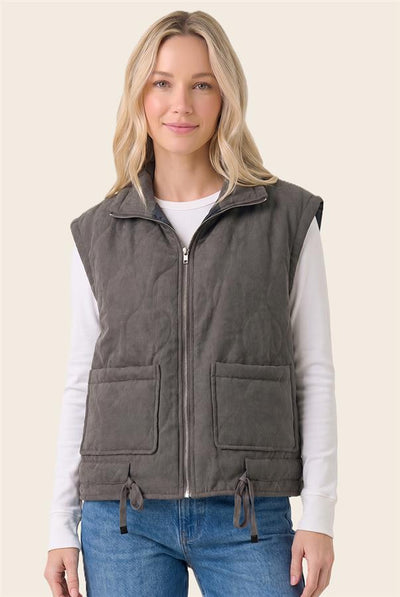 model wearing a white top & jeans with a charcoal vest and a light background