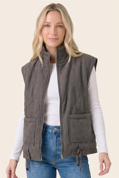 model wearing a white top & jeans with a charcoal vest and a light background