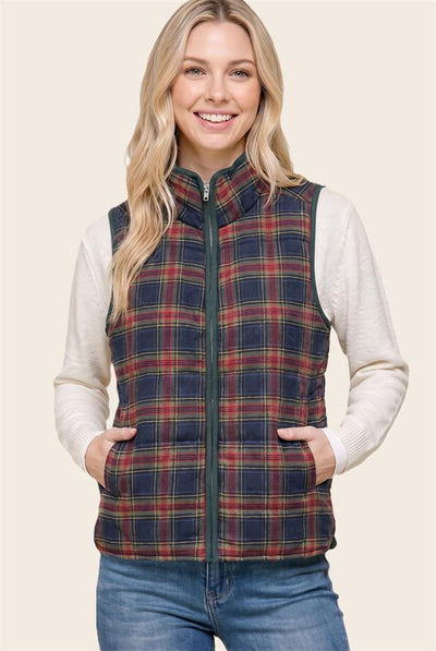 woman wearing a cream top and jeans with a navy/red/taupe plaid vest. her hands are in the pockets.