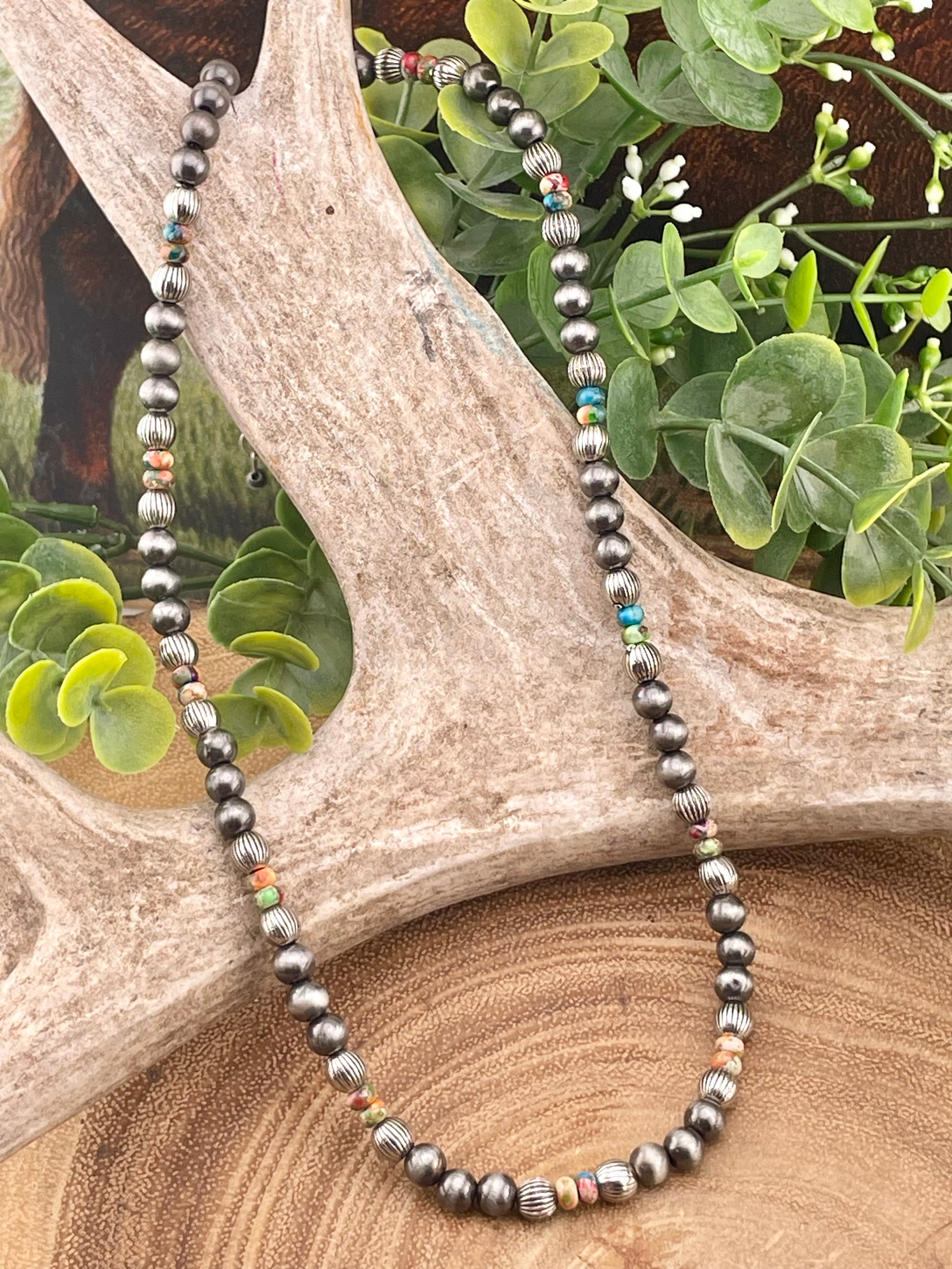 Necklace with beads on a wooden surface with greenery
