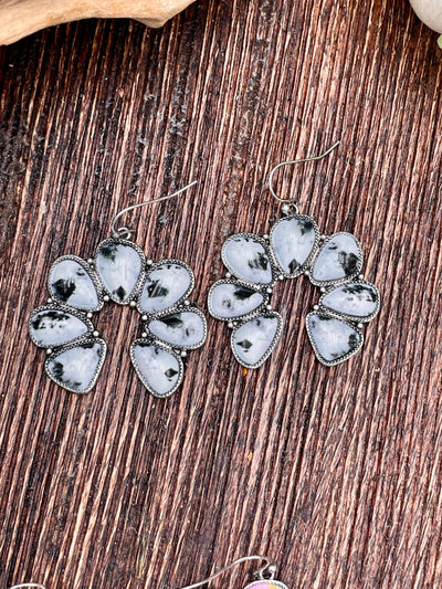 Black & White Naja earrings on a wooden surface