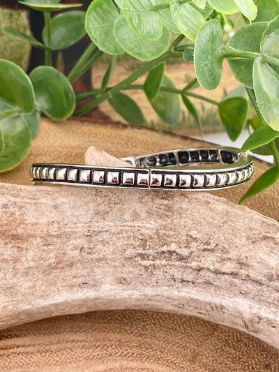 square studded silver bracelet on display