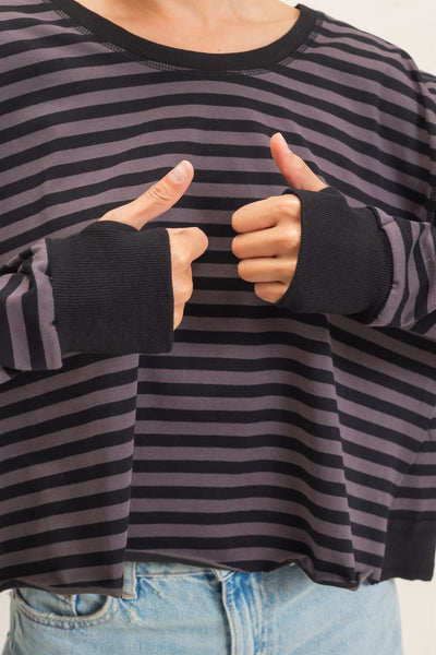 model wearing a black striped sweater and jeans with a light background