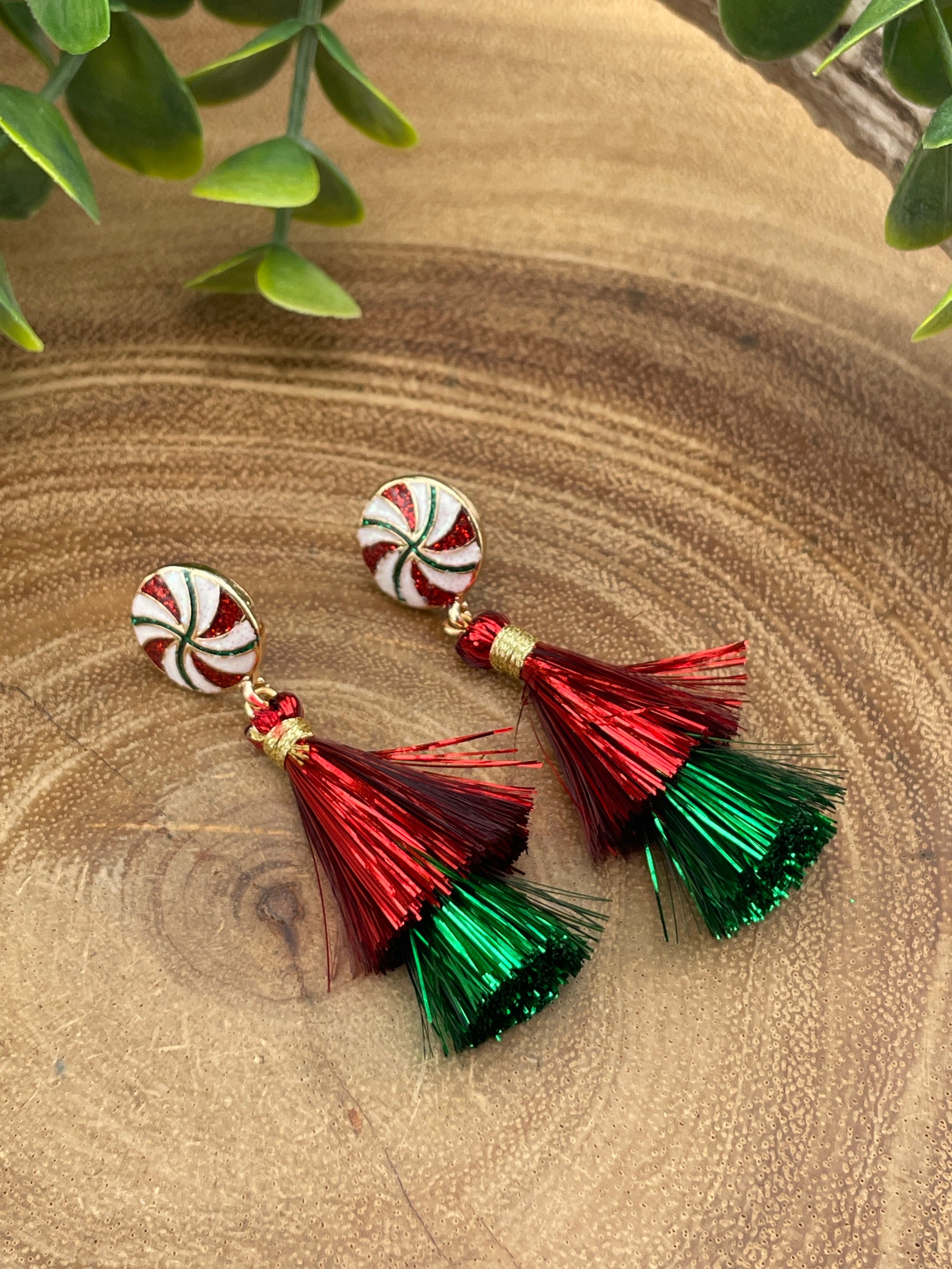 Pair of earrings with red and green tassels on a wooden surface