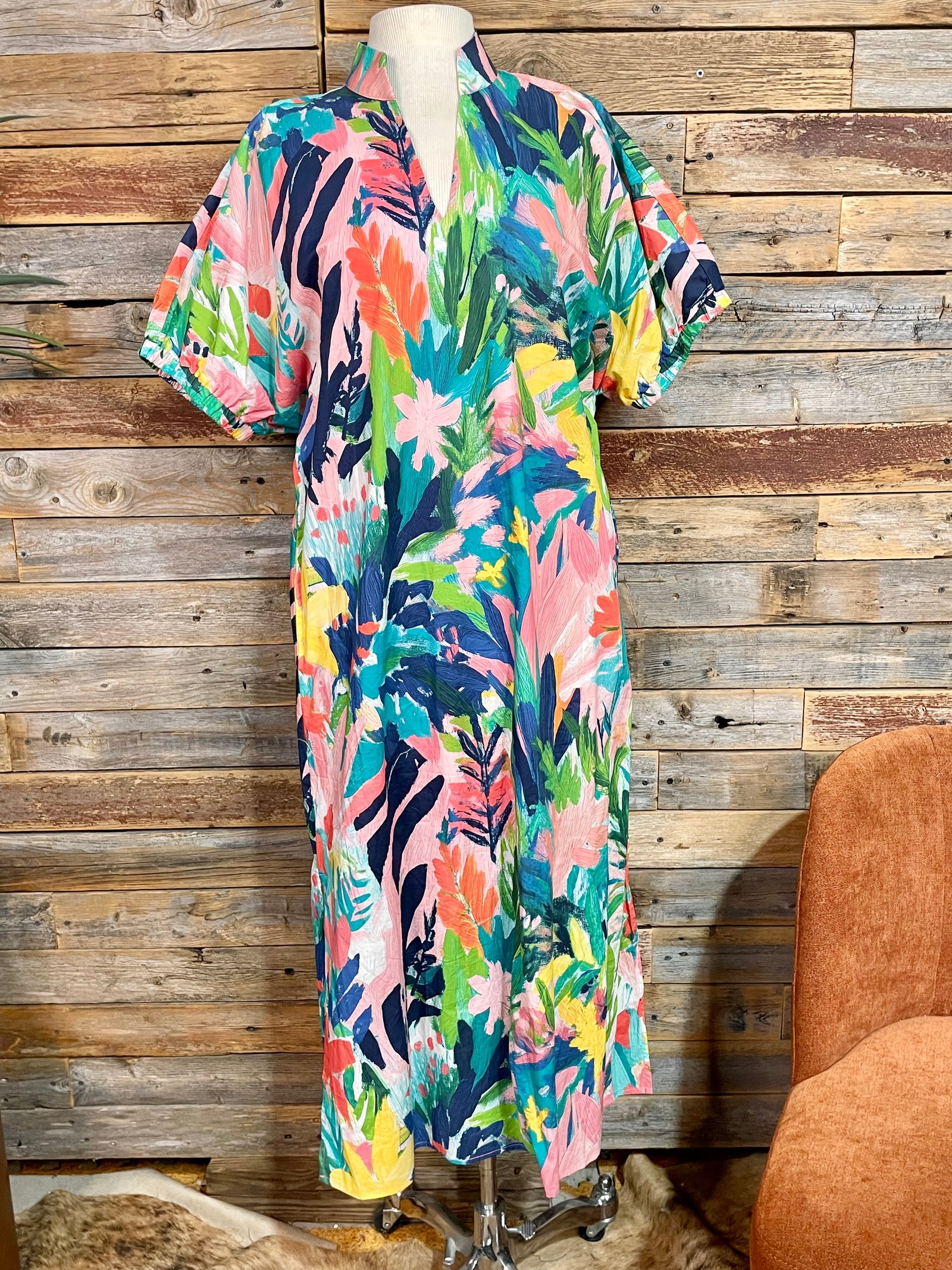 Colorful floral dress on a mannequin against a wooden wall.