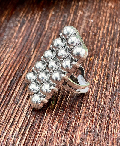 Silver ring with bead design on a wooden surface