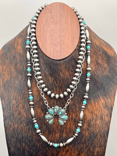Silver and turquoise beaded necklace on a wooden stand.