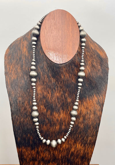 Silver beaded necklace on a wooden mannequin bust