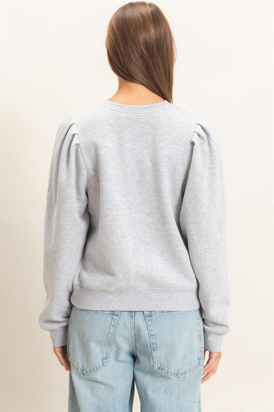 back of model wearing heather gray top and jeans in front of a light background