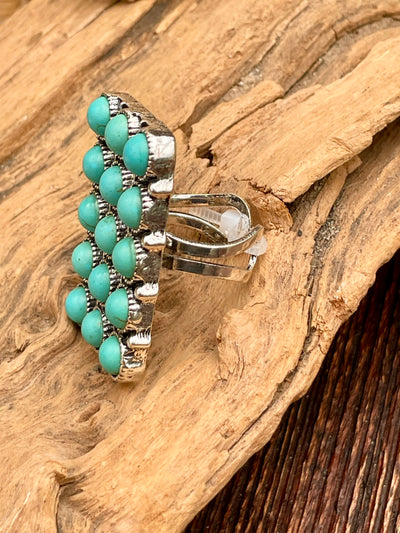 Silver ring with turquoise beads on a wooden surface