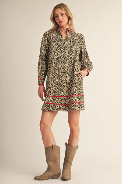 model wearing leopard dress with red accents and boots in front of a light background