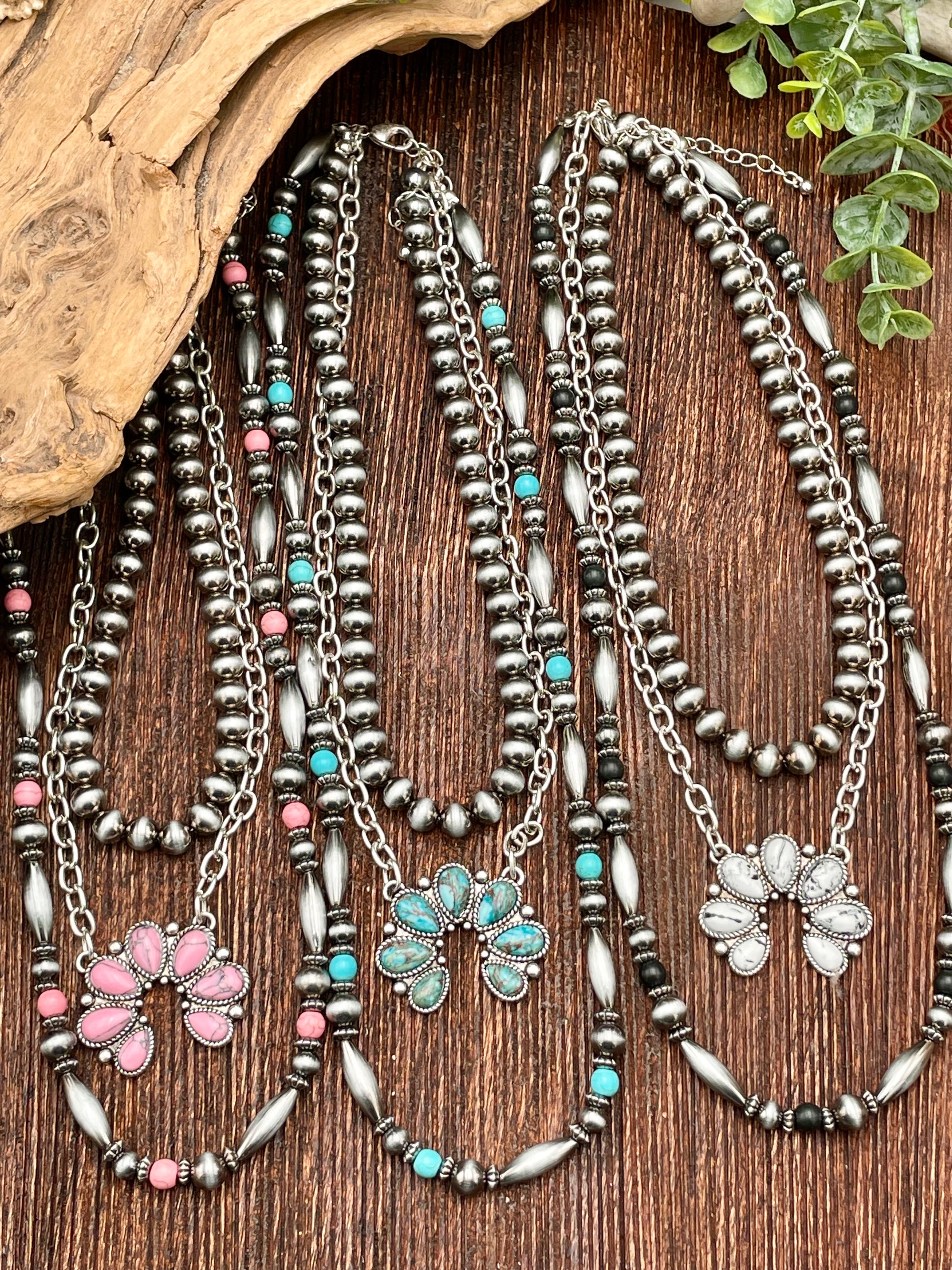 Set of beaded necklaces with floral pendants on a wooden surface