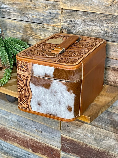 Brown leather box with cowhide pattern on a wooden surface
