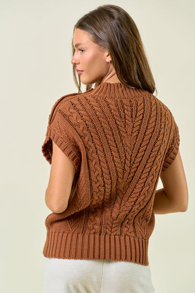Woman wearing a brown knitted vest against a plain background