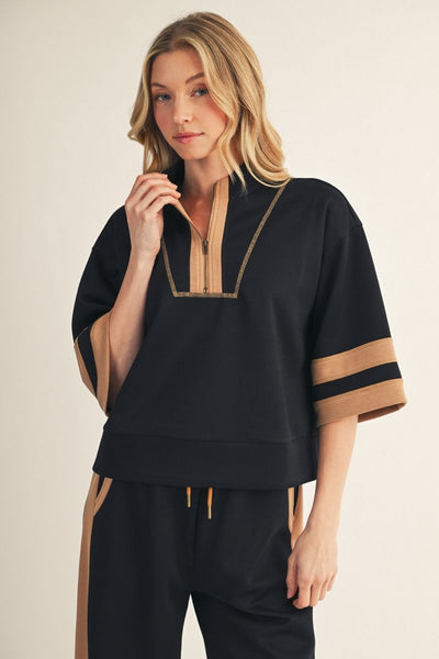 Woman wearing a black and beige outfit with a plain background