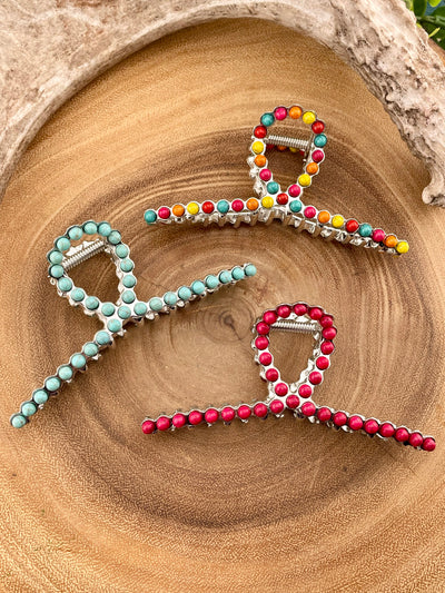 Three decorative hair clips with colorful beads on a wooden surface