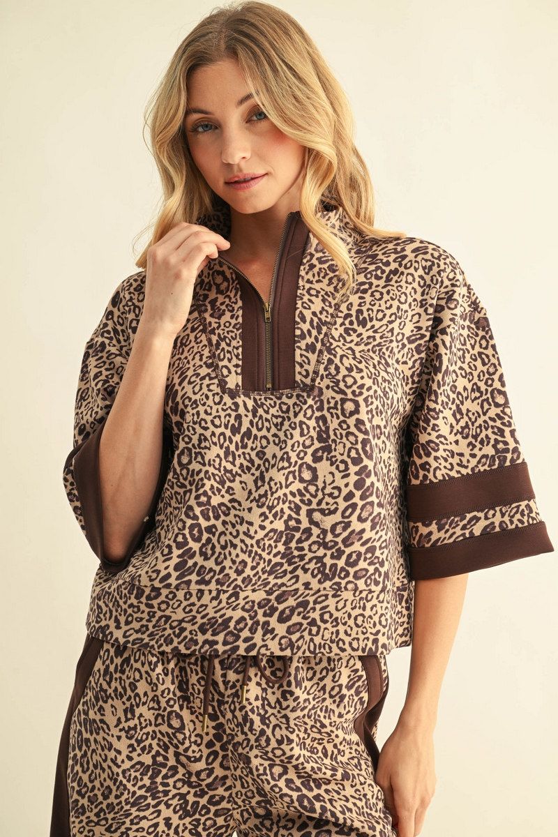 A woman modeling a matching two-piece lounge set featuring a brown and beige leopard print pattern with solid brown trim on a light beige studio background.