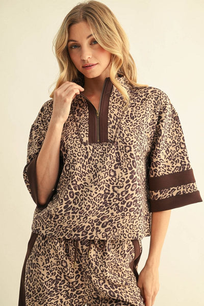 A woman modeling a matching two-piece lounge set featuring a brown and beige leopard print pattern with solid brown trim on a light beige studio background.