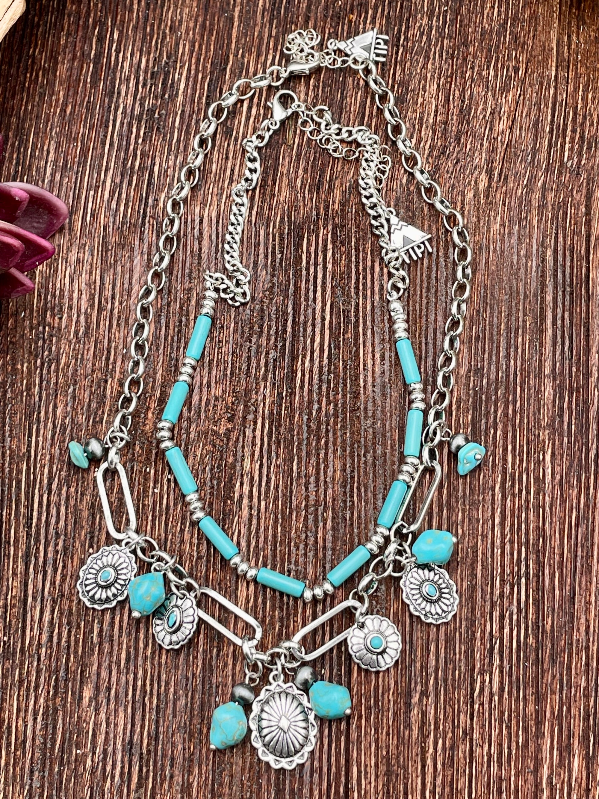 Necklace with turquoise beads and silver charms on a wooden surface