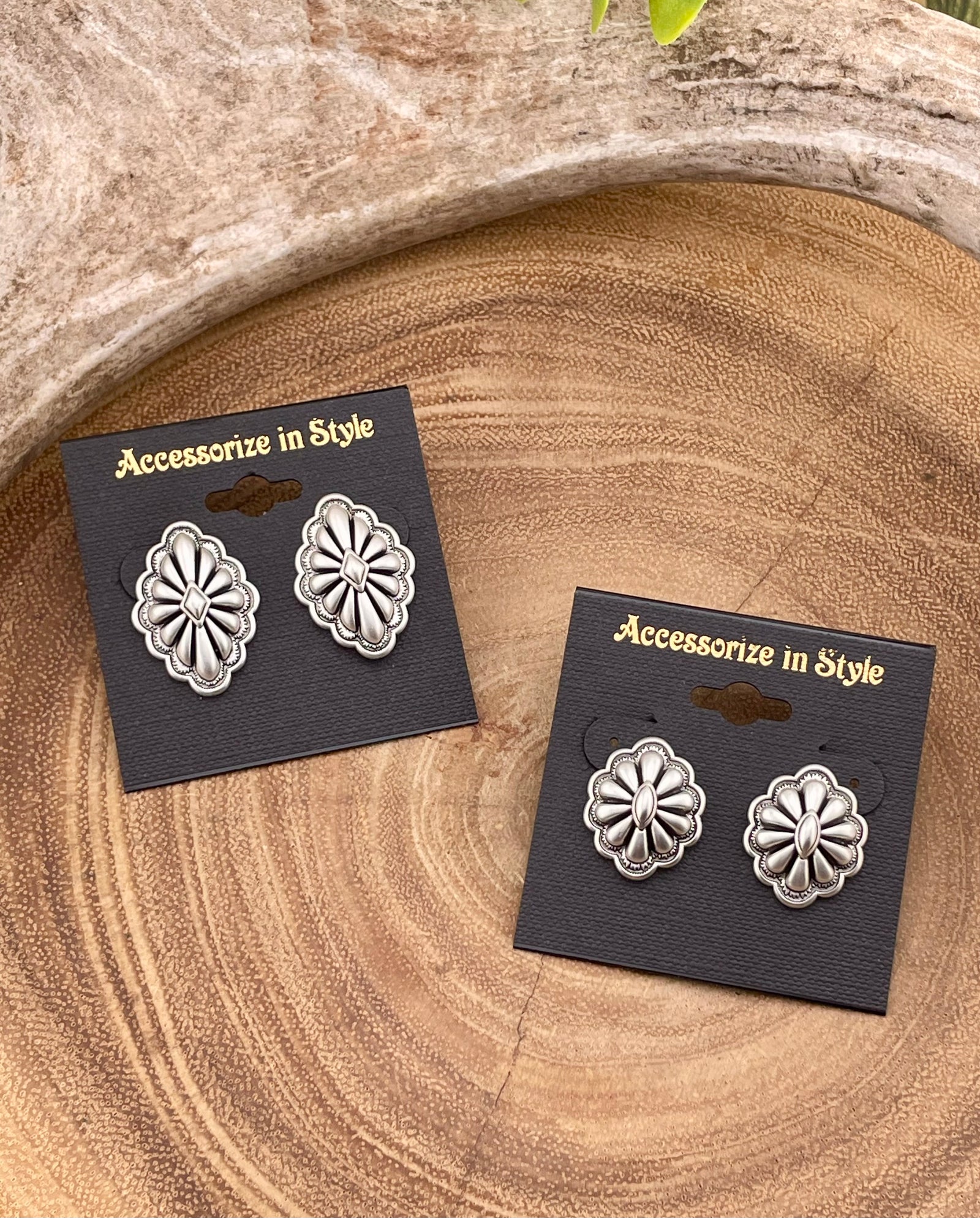 Pair of silver concho earrings on 'Accessorize in Style' cards on a wooden surface