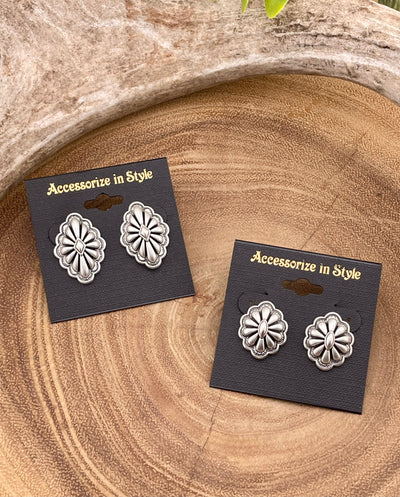 Pair of silver concho earrings on 'Accessorize in Style' cards on a wooden surface