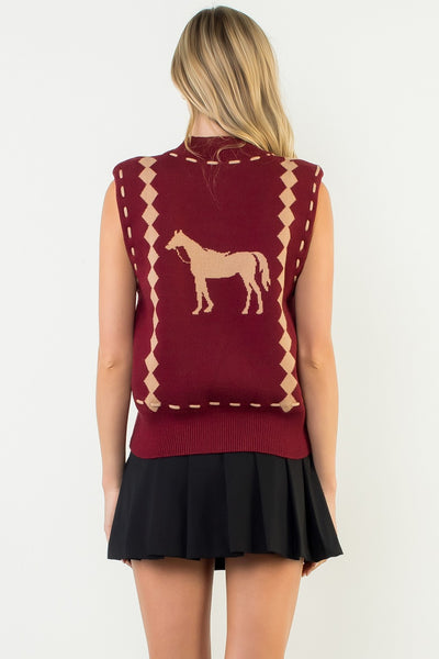 Woman wearing a maroon sleeveless sweater with a horse design on the back against a white background