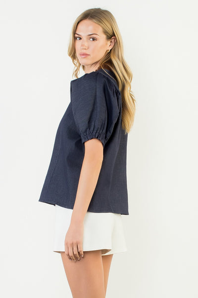 Woman wearing a navy blue top and white shorts on a plain background